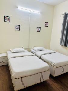 浦那Elite Stays Viman nagar的配有白色墙壁和木地板的客房内的三张床