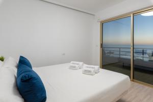 圣地亚哥港OBSIDIAN Mirador del Oceano的一张带蓝色枕头的白色床和一个阳台