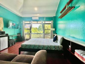 科罗尔Ngermid Oasis-Spacious Studio Loft W/ Garden Views的一间卧室配有一张床、一张沙发和一个窗口