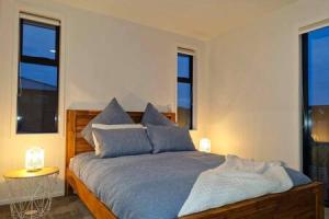 基督城Lovely Brand New Home的一间卧室配有一张带蓝色枕头的床和窗户。