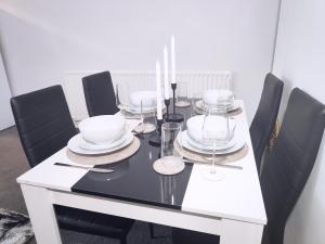 伍尔弗汉普顿Large 3 bed House Wolverhampton Families and Contractors的餐桌、黑色椅子和玻璃杯白桌