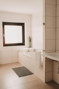艾琴堡Dorf 70的白色的浴室设有浴缸和窗户。