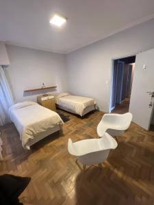 马德普拉塔Habitaciones Garay 3100的一间设有两张床和白色椅子的房间