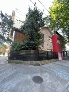 马德普拉塔Habitaciones Garay 3100的街道旁的红色房子,有栅栏