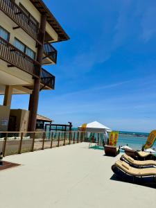 拉巴拉德纳圣米格尔Apartamento em Barra Bali, Resort de Luxo, Barra de São de Miguel - 223的海滩上,有椅子,还有一座建筑和大海