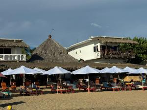 兹波利特Che Zipolite Hostel & Naked Beach Club的海滩上一组桌椅和遮阳伞