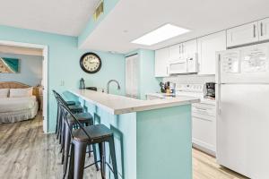 基韦斯特Sunrise Suites Barbados Suite #204的厨房设有蓝色的墙壁和带凳子的台面。