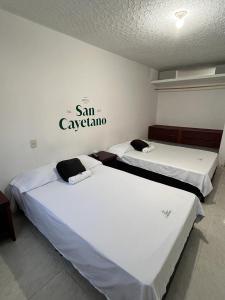 OcañaHotel San Cayetano的墙上有标牌的房间的两张床