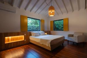 蓬塔德尔加达Carmo Country Villas的一间卧室配有一张床、一张沙发和两个窗户。