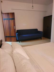 斯里贾亚瓦德纳普拉科特M-stay Colombo的一间卧室配有一张床和一张蓝色的沙发