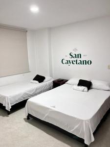 OcañaHotel San Cayetano的墙上有标牌的房间的两张床