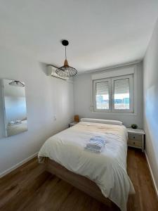 贝尼卡西姆Apartamento Benicàssim Sunset Calm&Views的一间白色卧室,配有床和2个窗户