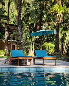 多米尼克Rio Lindo Hotel的游泳池旁的两把椅子和一把遮阳伞