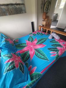 旺阿帕劳阿Stanmore Bay Beachfront Cottage的一张带蓝色棉被的床,上面有粉红色的花朵