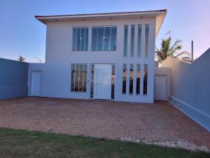 布罗塔斯Pousada Recanto Luigi的白色的房子,有玻璃门和砖车道