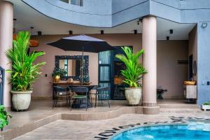 卡利Hotel Osvé Boutique Cali的庭院设有带遮阳伞的桌子和游泳池。