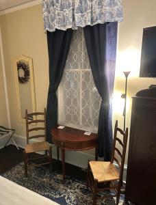 谢尔比维尔Belmont Inn的一间卧室配有书桌、两把椅子和窗帘