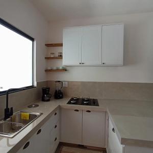 巴拉那州蓬塔尔Ap 01 apartamento Beira mar的厨房配有白色橱柜、水槽和窗户。