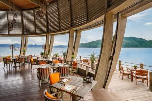 宁凡湾宁凡湾安拉姆度假酒店的一间带桌椅并享有水景的餐厅