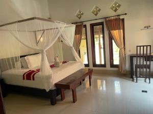 特贾库拉Teluk Karang Dive & Spa Resort的一间卧室配有天蓬床和长凳