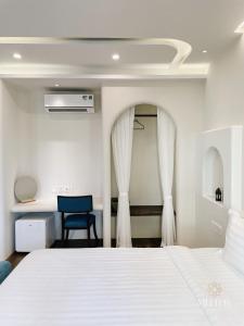 富国Mellon OASIS Phu Quoc的卧室配有白色的床和蓝色椅子