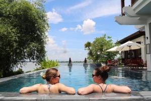 会安Nghê Prana Villa & Spa Hoi An的两名女性在度假村的游泳池游泳