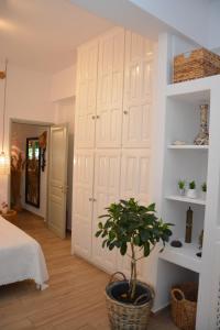 斯科拉Patmos Little Suites的卧室配有带盆栽的大白色衣柜