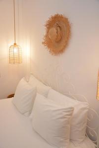 斯科拉Patmos Little Suites的白色的床、白色枕头和墙上的镜子