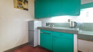 马尼拉RedDoorz at Broadway Court Apartelle II Quezon City的厨房配有绿色橱柜和白色冰箱