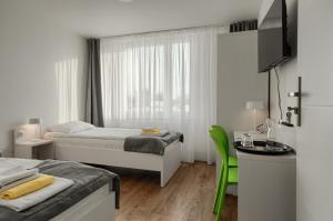 什切青Płonia Resort的白色的客房设有两张床、一张桌子和一张书桌。