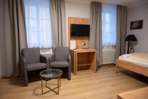 代德斯海姆Hotel & Café Ritter von Böhl的酒店客房配有一张床、一把椅子和一台电视。