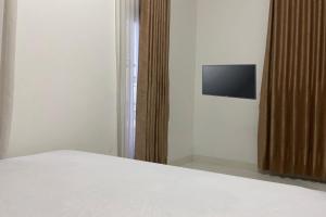 查亚普拉OYO 93485 Hotel Kenzie Sentani的卧室配有一张床,墙上配有电视。