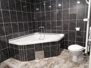 VojnikHostel Vojnik的黑色瓷砖浴室设有浴缸和卫生间