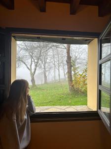 PiloñaLa Casona de Soviña的看着窗外田野的女孩