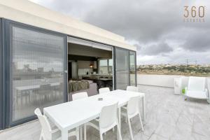 San ĠwannLUX Duplex Penthouse w/ Expansive Rooftop Terrace by 360 Estates的阳台上配有白色的桌椅