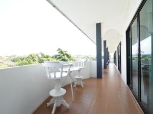 邦萨雷RoomQuest One Bangsaray的阳台配有白色椅子和桌子。