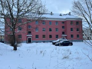 TapaSaunaga korter Tapa kesklinnas!的一座红色的建筑,有一辆汽车停在雪覆盖的院子内