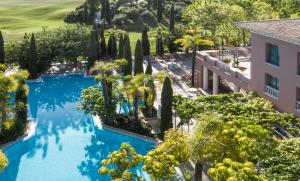EsteponaAnantara Villa Padierna Palace Benahavís Marbella Resort - A Leading Hotel of the World的享有树木游泳池和大楼的顶部景色