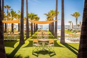 EsteponaAnantara Villa Padierna Palace Benahavís Marbella Resort - A Leading Hotel of the World的一间种有棕榈树的餐厅,配有桌椅
