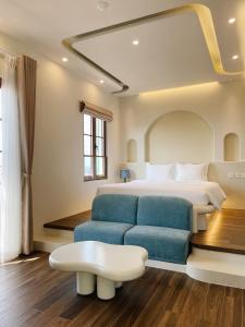 富国Mellon OASIS Phu Quoc的一间卧室配有一张床和一张蓝色的沙发