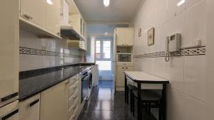 格乔Maravillosa ubicación junto al mar con garaje的厨房配有白色橱柜和黑色台面