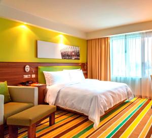 华沙华沙市中心希尔顿汉普顿酒店的卧室配有床、椅子和窗户。