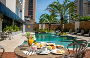 伊瓜苏拉费恩中心酒店的一个带游泳池的阳台,配有一张桌子,上面摆放着食物和饮料