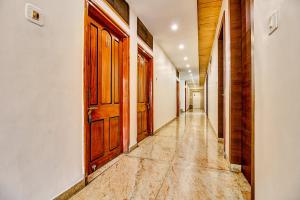 博帕尔FabHotel Manjeet的空的走廊,设有木门,铺着瓷砖地板