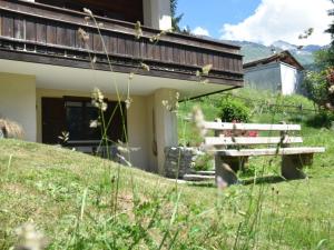 库尔瓦尔登Apartment Am Sonnenhang by Interhome的坐在建筑物旁边的草上木凳