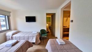 圣卡洛斯-德巴里洛切M382 Hotel Bariloche的酒店客房,设有两张床和一把绿色椅子
