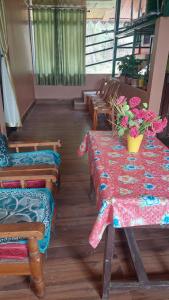 大吉岭Athithi homestay的一间设有桌椅的房间,上面摆放着鲜花