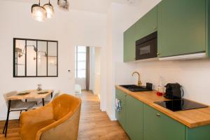 桑斯Le Laurencin Sens - Le Keys的厨房配有绿色橱柜和桌椅