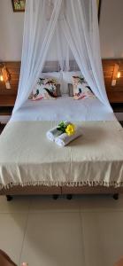 因巴塞Casa noites tropicais的一张带白色天篷的床,上面有鲜花
