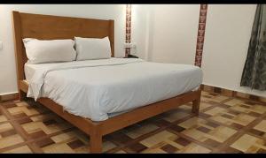 穆索里FabHotel Rudraksh Resort的卧室内的一张带白色床单和枕头的床